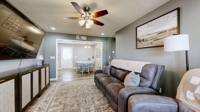 living area featuring baseboards, ceiling fan, recessed lighting, wood finished floors, and a textured ceiling