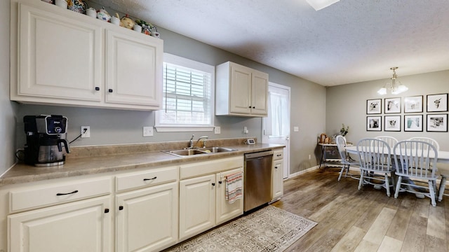 kitchen with a notable chandelier, light wood-style flooring, a sink, a textured ceiling, and dishwasher