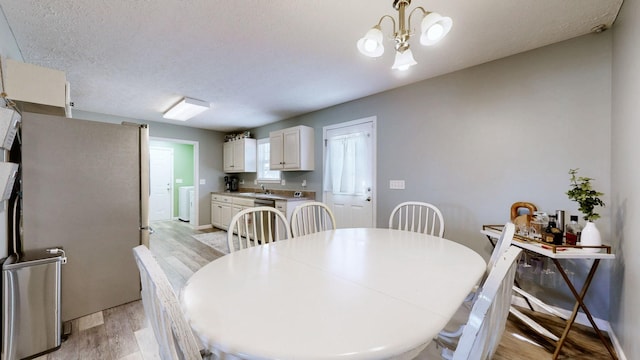 dining space with a notable chandelier, baseboards, light wood-type flooring, and a textured ceiling