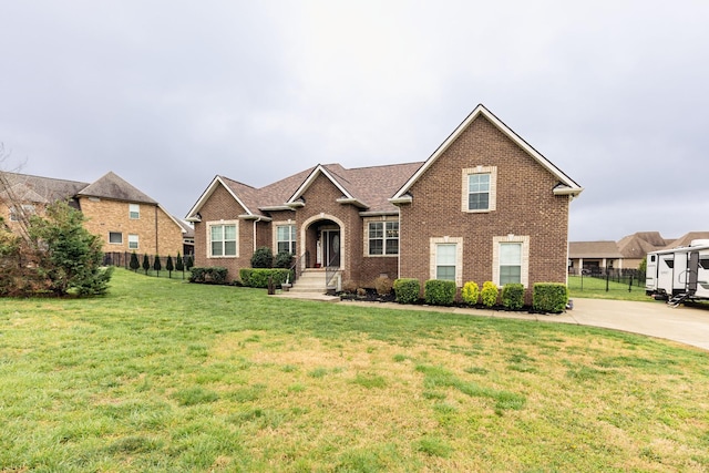 view of front facade with brick siding, fence, and a front yard