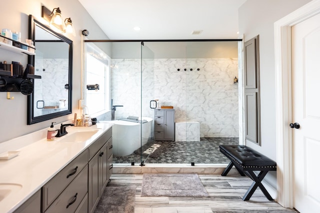 full bathroom with a freestanding bath, a sink, a stall shower, and double vanity