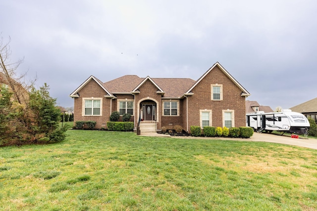 single story home featuring brick siding, a shingled roof, a front lawn, and concrete driveway