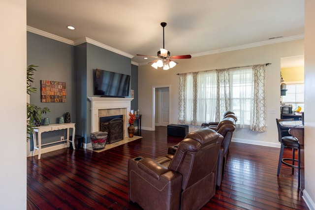 living room with a ceiling fan, a tiled fireplace, ornamental molding, and hardwood / wood-style floors