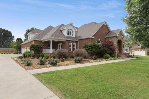 view of front of home with concrete driveway, a porch, and a front yard