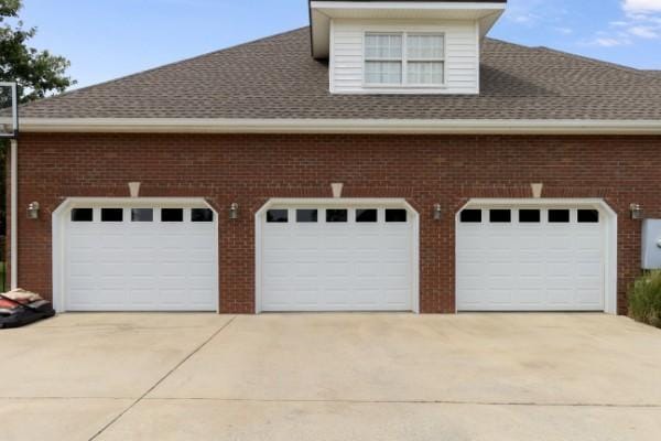 exterior space with concrete driveway, brick siding, roof with shingles, and a garage