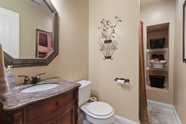 bathroom with baseboards, vanity, and toilet