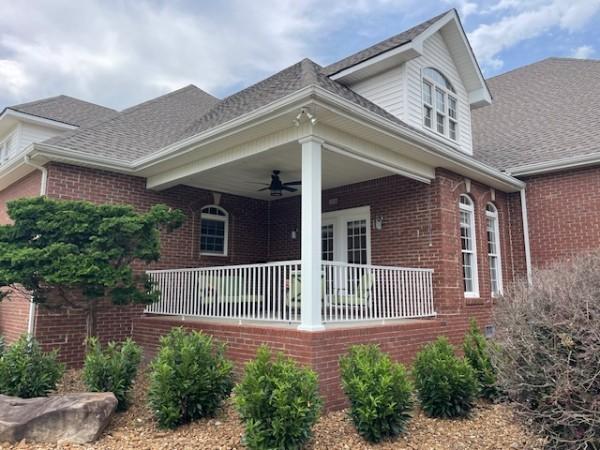 view of front facade with a porch, ceiling fan, and brick siding