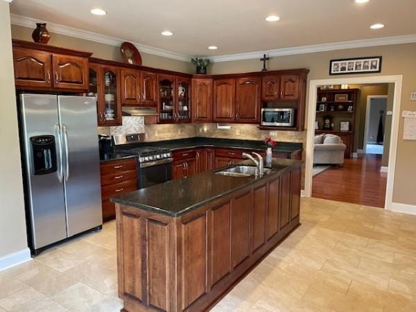 kitchen with backsplash, under cabinet range hood, dark countertops, and stainless steel appliances