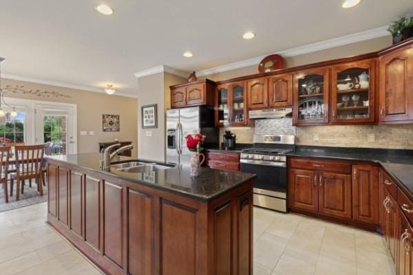 kitchen with stainless steel appliances, a sink, dark countertops, under cabinet range hood, and ornamental molding
