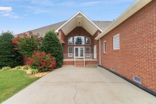 entrance to property with brick siding, french doors, and visible vents