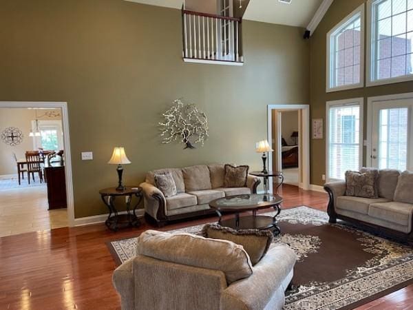 living area featuring wood finished floors, baseboards, and high vaulted ceiling