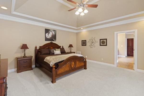 bedroom featuring light carpet, baseboards, a raised ceiling, and ornamental molding