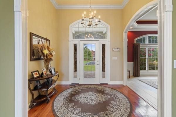 foyer with ornamental molding, an inviting chandelier, and a healthy amount of sunlight
