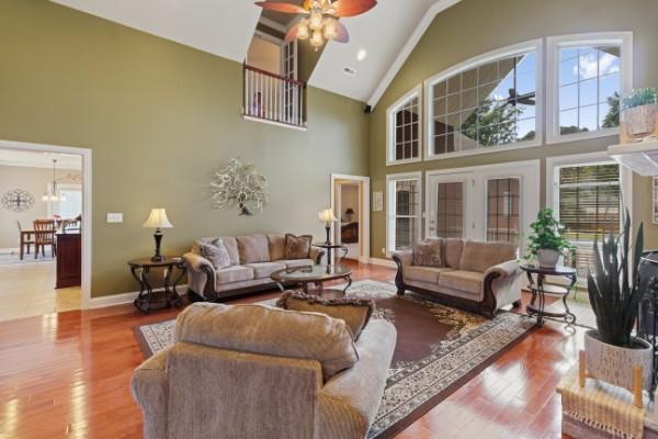 living area with high vaulted ceiling, ceiling fan, baseboards, and wood finished floors
