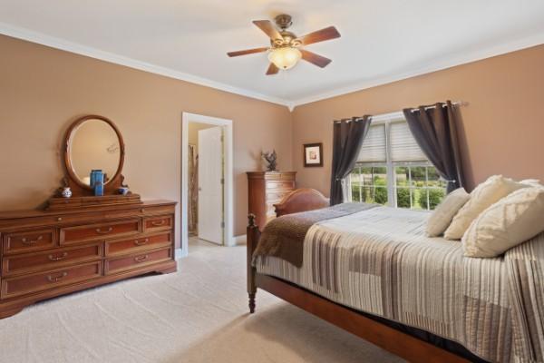 bedroom featuring ceiling fan, baseboards, crown molding, and carpet flooring