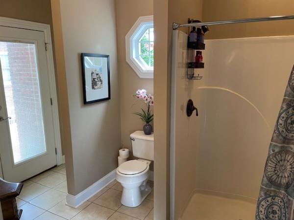 bathroom with a shower stall, baseboards, toilet, and tile patterned floors