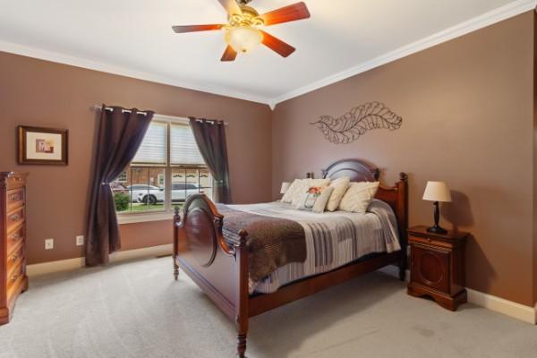 bedroom featuring ornamental molding, baseboards, and light colored carpet
