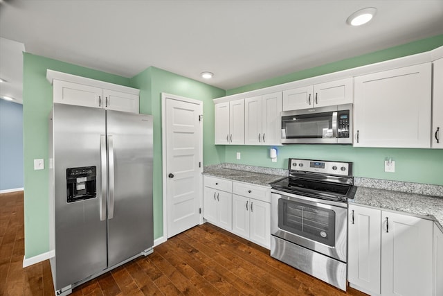kitchen with light stone countertops, baseboards, dark wood-style flooring, white cabinets, and appliances with stainless steel finishes