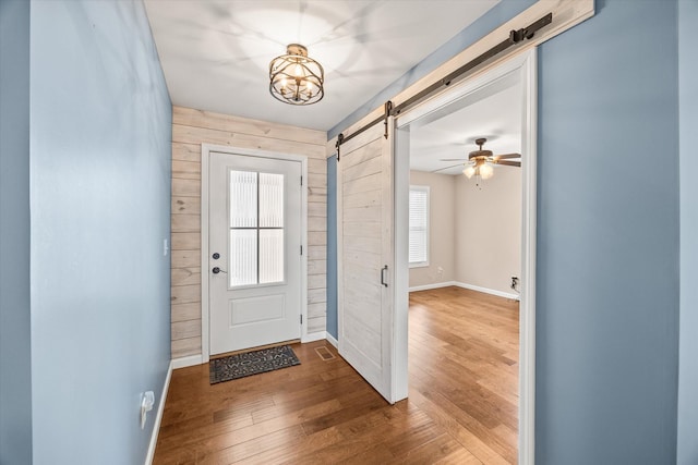 entryway featuring a barn door, baseboards, wooden walls, and hardwood / wood-style floors