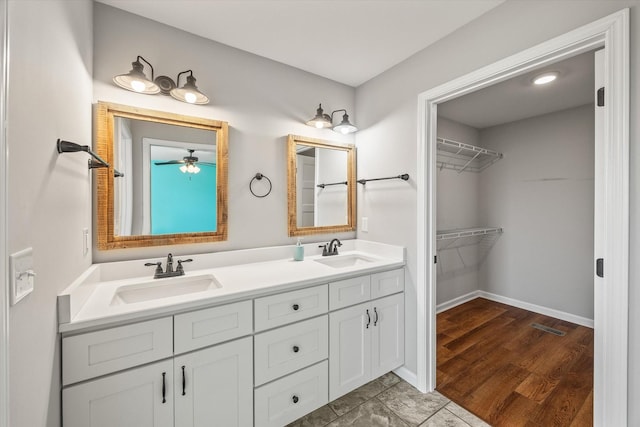 bathroom featuring a walk in closet, double vanity, visible vents, and a sink