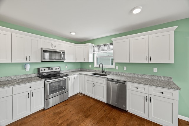 kitchen with white cabinetry, dark wood-type flooring, appliances with stainless steel finishes, and a sink