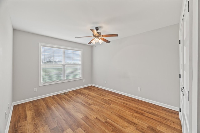 empty room with visible vents, baseboards, a ceiling fan, and wood finished floors