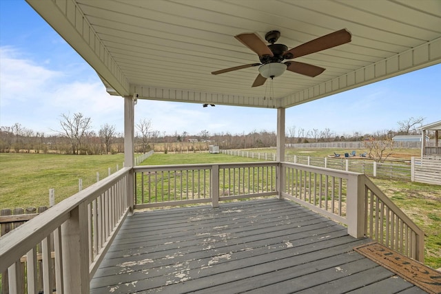 wooden deck featuring fence, a lawn, ceiling fan, and a rural view