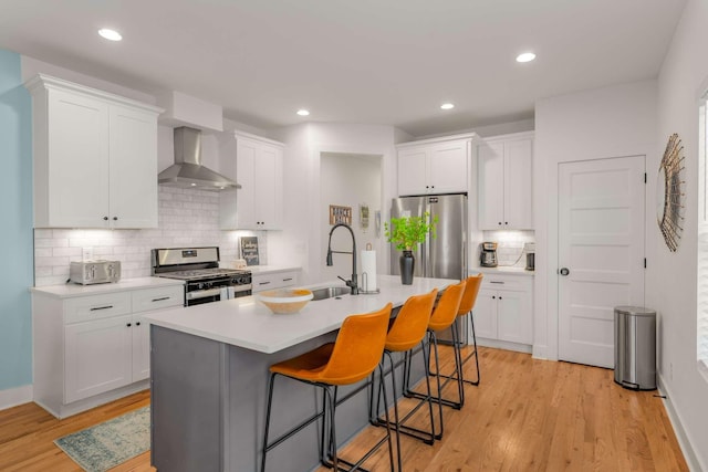 4009B Indiana Ave, Nashville, TN 37209 - kitchen with a breakfast bar area, appliances with stainless steel finishes, white cabinetry, wall chimney exhaust hood, and a sink