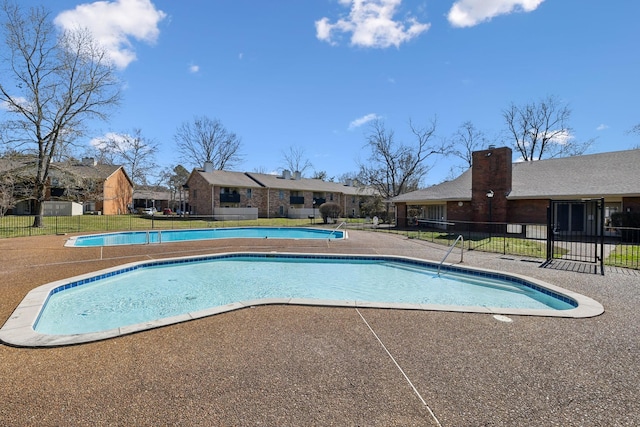 pool with a patio area, fence, and a residential view