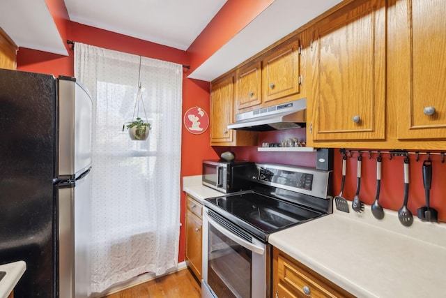 kitchen featuring light wood-style flooring, stainless steel appliances, light countertops, under cabinet range hood, and brown cabinets