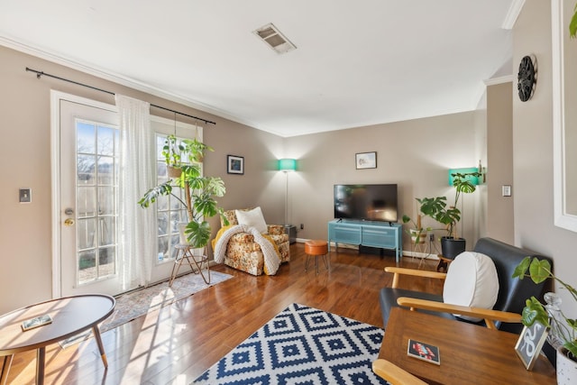 living room with crown molding, wood finished floors, and visible vents