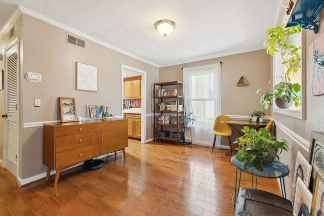 sitting room featuring visible vents, light wood-type flooring, baseboards, and ornamental molding
