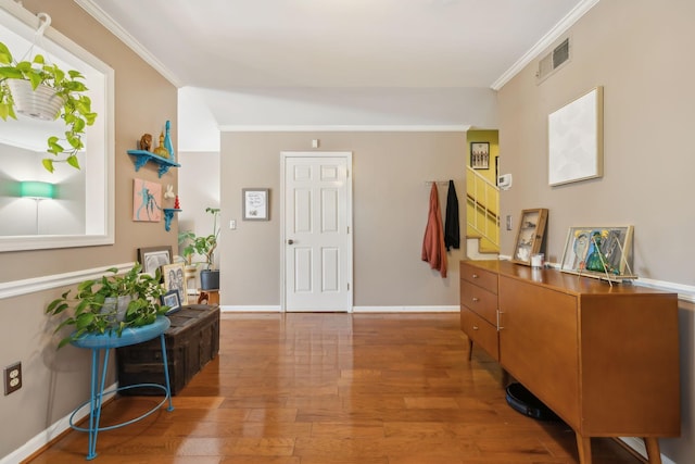 foyer featuring crown molding, wood finished floors, visible vents, and baseboards