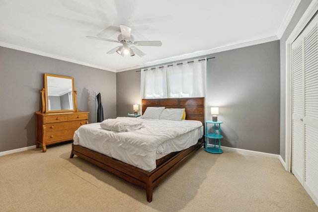 carpeted bedroom with ceiling fan, a closet, baseboards, and ornamental molding