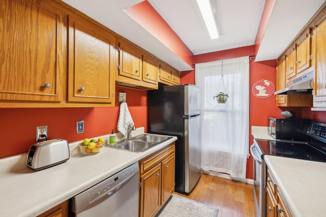 kitchen with light countertops, brown cabinets, under cabinet range hood, and stainless steel appliances