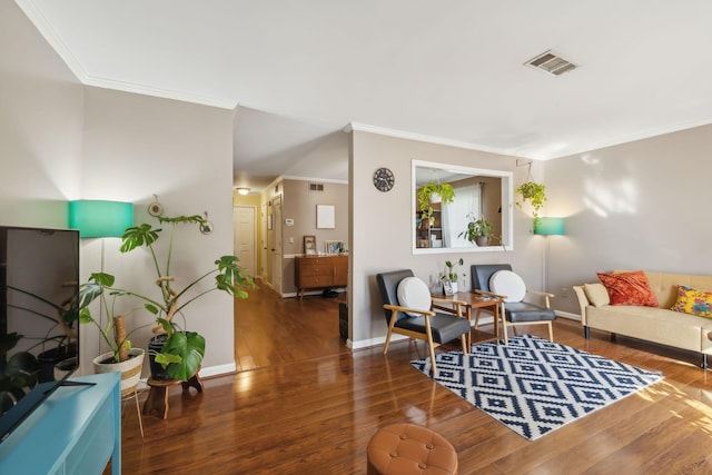 living area with visible vents, ornamental molding, baseboards, and wood finished floors