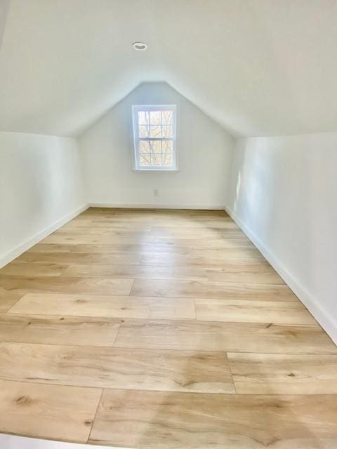 additional living space with baseboards, wood finished floors, and vaulted ceiling