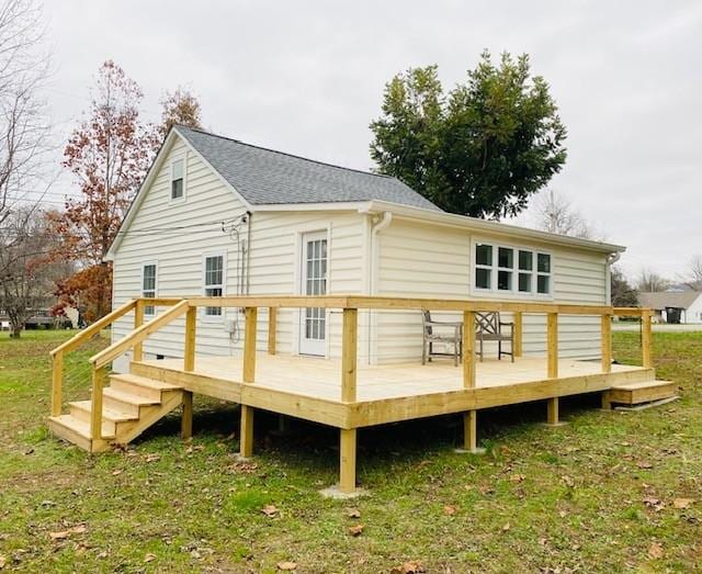 back of house with a yard, roof with shingles, and a wooden deck