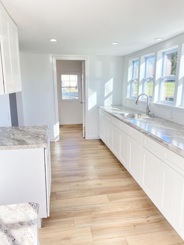 kitchen featuring white cabinetry, light wood-style flooring, recessed lighting, and a sink