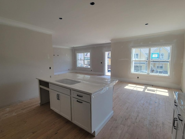kitchen featuring wood finished floors, a kitchen island, white cabinetry, open floor plan, and crown molding