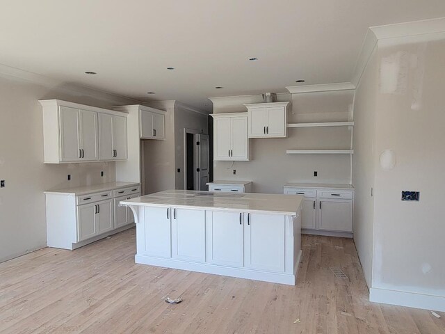 kitchen featuring white cabinets, light wood-type flooring, crown molding, and a kitchen island