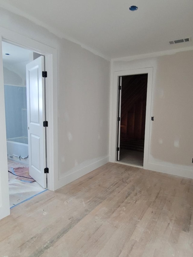 empty room with baseboards, visible vents, and wood finished floors