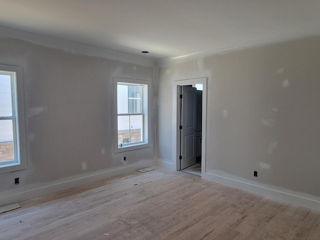 spare room featuring ornamental molding, light wood-style flooring, and baseboards