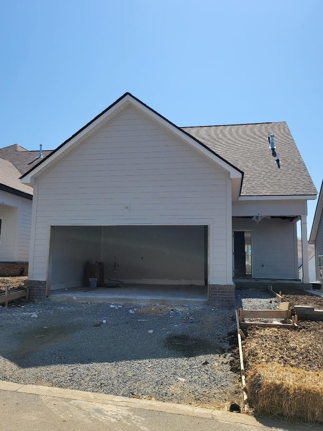 ranch-style house featuring driveway, a shingled roof, and a garage