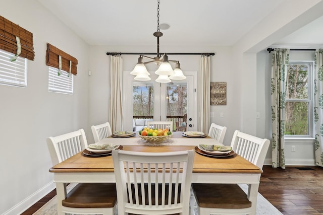 dining area with a chandelier, dark wood finished floors, baseboards, and a wealth of natural light