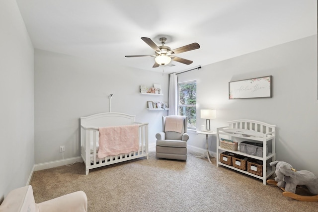 bedroom featuring baseboards, carpet floors, a crib, and a ceiling fan
