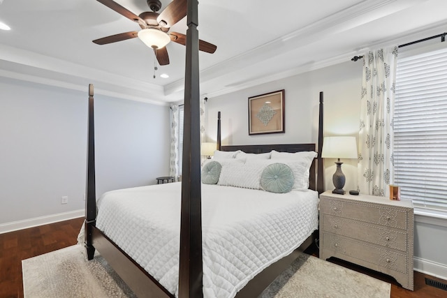 bedroom featuring visible vents, crown molding, baseboards, a tray ceiling, and wood finished floors