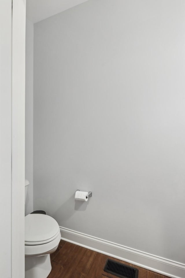 bathroom with toilet, wood finished floors, visible vents, and baseboards