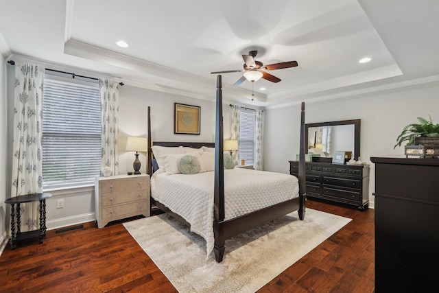 bedroom featuring crown molding, ceiling fan, baseboards, dark wood finished floors, and a tray ceiling