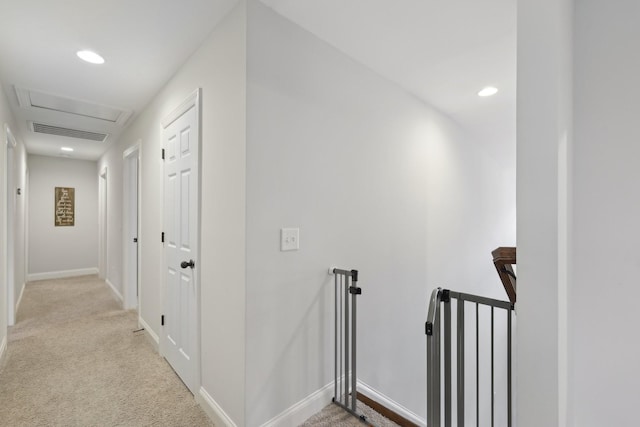 hallway featuring light colored carpet, an upstairs landing, visible vents, and baseboards